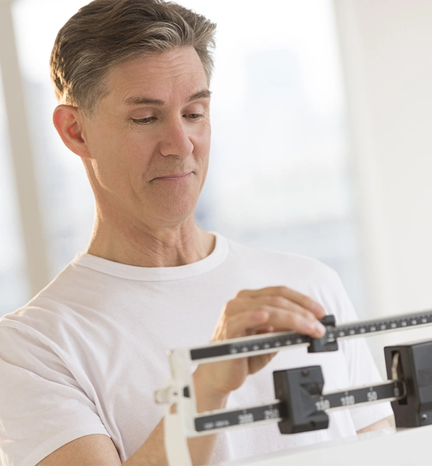 Mature man using scale to measure his weight